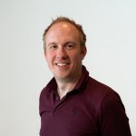 Michael MacCauley Audiologist at Amplify Hearing wears a maroon polo shirt for a professional head shot